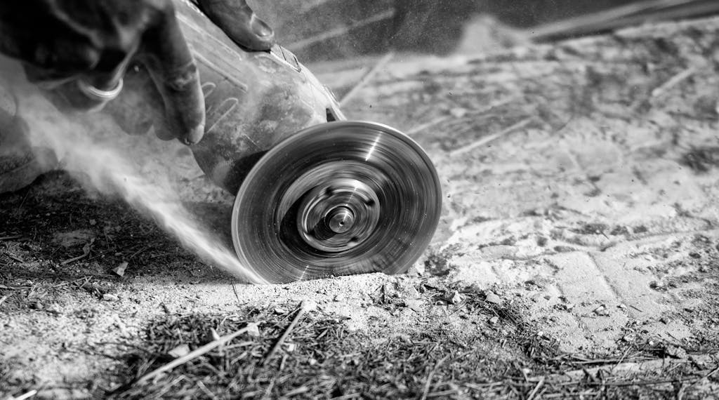 Dynamic black and white photo of a circular saw in action cutting stone surface.